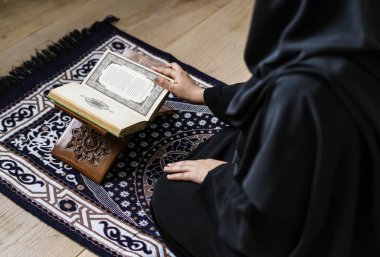 Muslim woman in black hijab reading Holy Koran, cropped image clipart