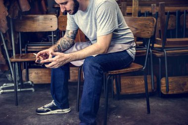 Oturan adam sandalyenin üstünde istimal hareket eden telefon