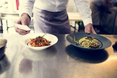 Şef mutfakta spagetti pişiriyor.
