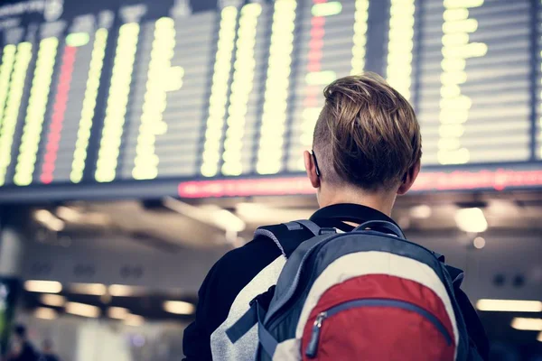 Arkadan Görünüş Genç beyaz çocuğun havaalanında uçuş programı kontrol