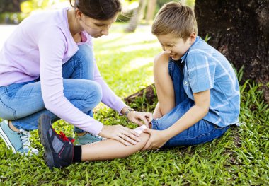 Küçük çocuk, anne oğul bacakta alçı yapıştırma oynarken bacağını alıntı