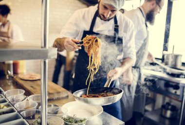 Şef mutfakta spagetti pişiriyor.