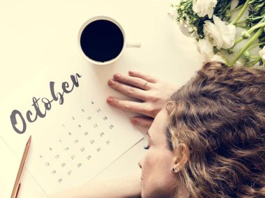 Uyuyan kadın kahve fincanı ve çiçekler ile Ekim takvim masada yatan yorgun 