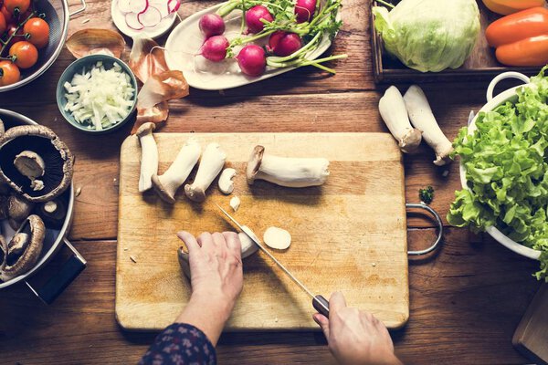 Aerial view of hand with knife cutting mushroom