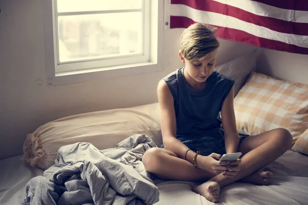 Jovem Caucasiano Menino Sentado Usando Telefone Celular Cama — Fotografia de Stock