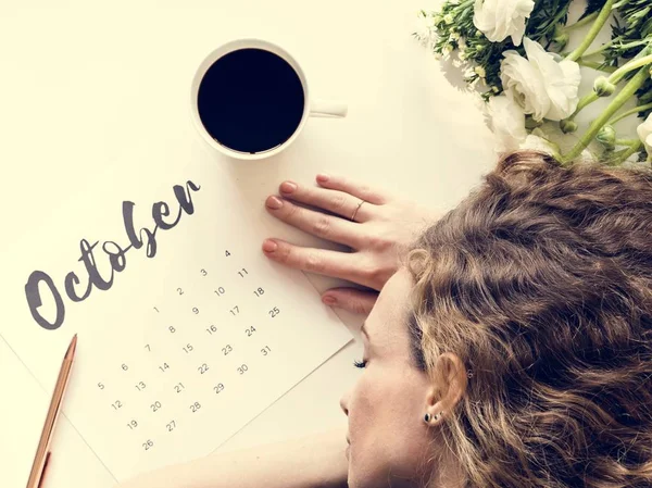 Uyuyan kadın kahve fincanı ve çiçekler ile Ekim takvim masada yatan yorgun 