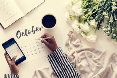 Ekim takvimde yazma ve cep telefonu tutan kadın 