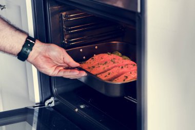 Çiğ somon steak fırına koyarak adam