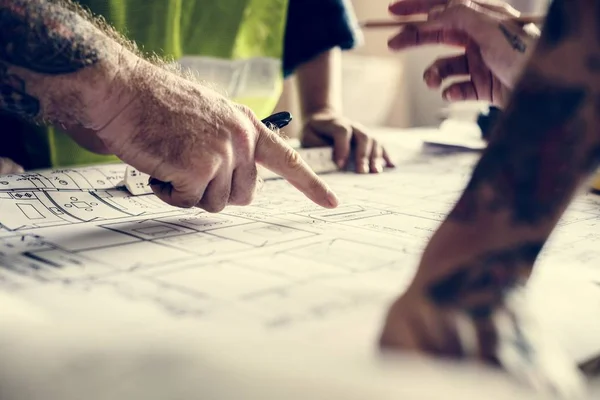 Hands with tattoo working on a blueprint — Stock Photo, Image