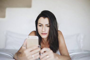 Yatakta bir cep telefonu kullanan kadın