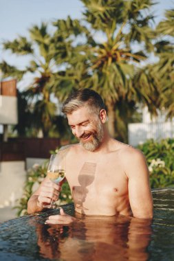 Bir bardak şarap havuza sahip yakışıklı adam