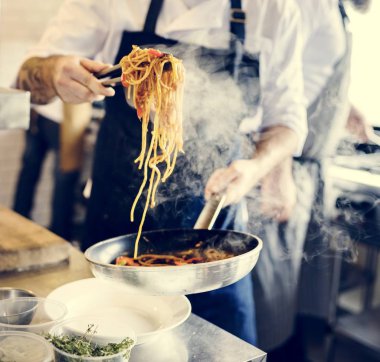 Şef mutfakta spagetti pişiriyor.