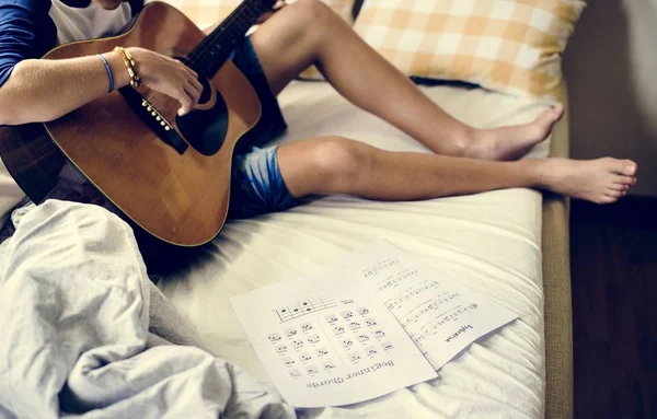 年轻的白种男孩在床上弹吉他特写 — 图库照片