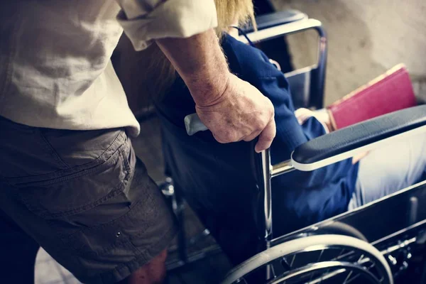 年配の男性が女性の車椅子を押してのクローズ アップ — ストック写真