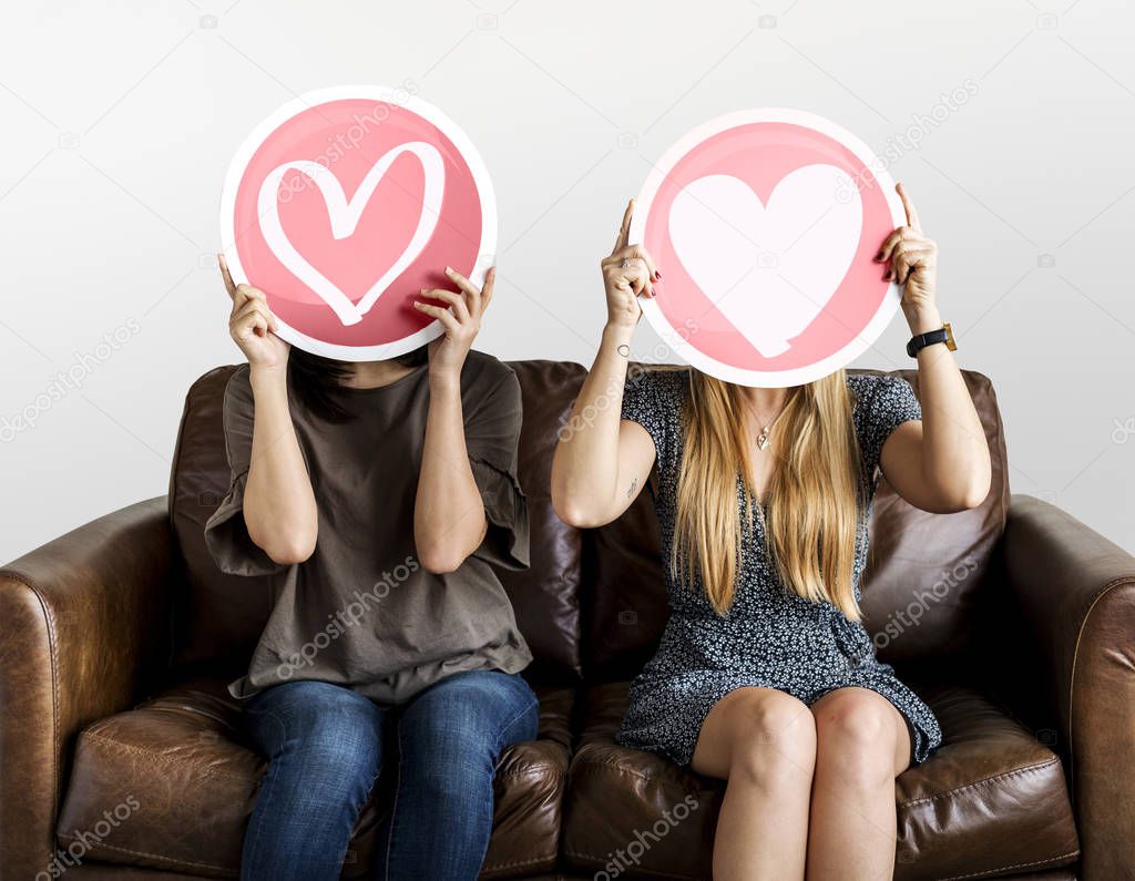 two Women holding up valentine icons with hearts