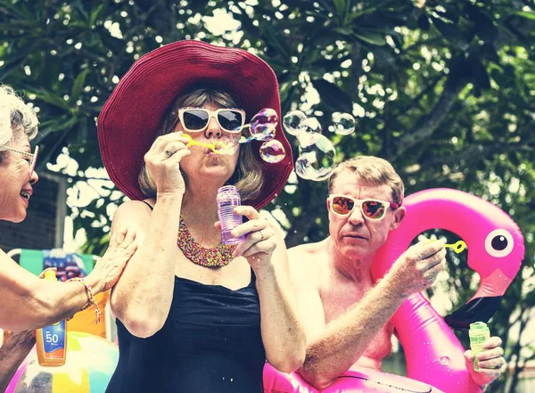 Group Diverse Senior Adults Sitting Poolside Blowing Soap Bubbles — Stock Photo, Image