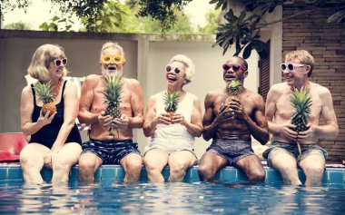 Grup ananas bir arada tutan havuz kenarında oturan farklı kıdemli Yetişkin