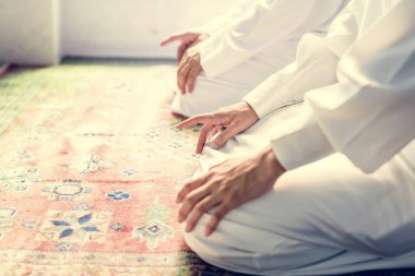 Müslüman erkeklerin dua Teşehhüt duruş, halının üzerinde oturan insanların kırpılmış görüntü