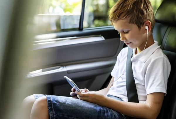 stock image Boy with earphones playing on a smartphone in the car