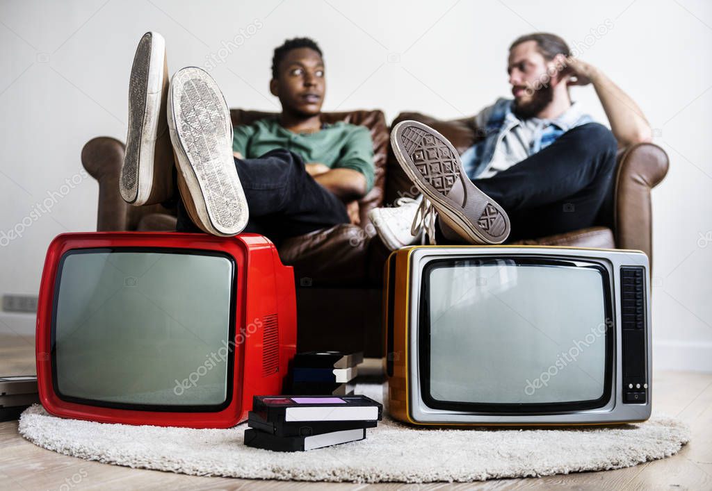 Two man sitting and two retro television