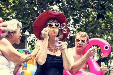 Grup sabun köpüğü üfleme havuz kenarında oturan farklı kıdemli yetişkin