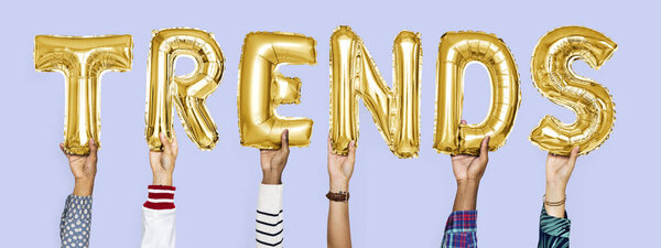 Yellow gold alphabet helium balloons forming the text trends