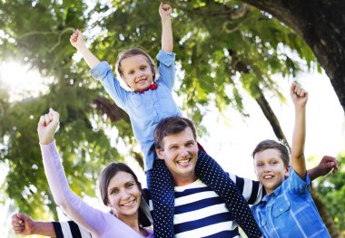 Aile parkı ve eller yukarı, baba omuzlarında oturan kızı eğleniyor