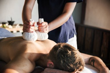 Adam bir bitkisel sahip bir Spa'da masaj sıkıştırmak