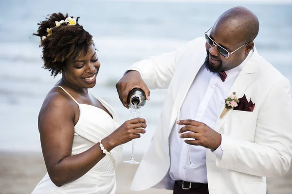 ビーチでシャンパンとアフリカ系アメリカ人の結婚式のカップル — ストック写真