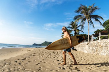 Bir adam sahilinde bir surfboard ile