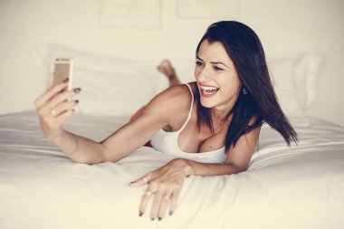 Yatakta bir cep telefonu kullanan kadın