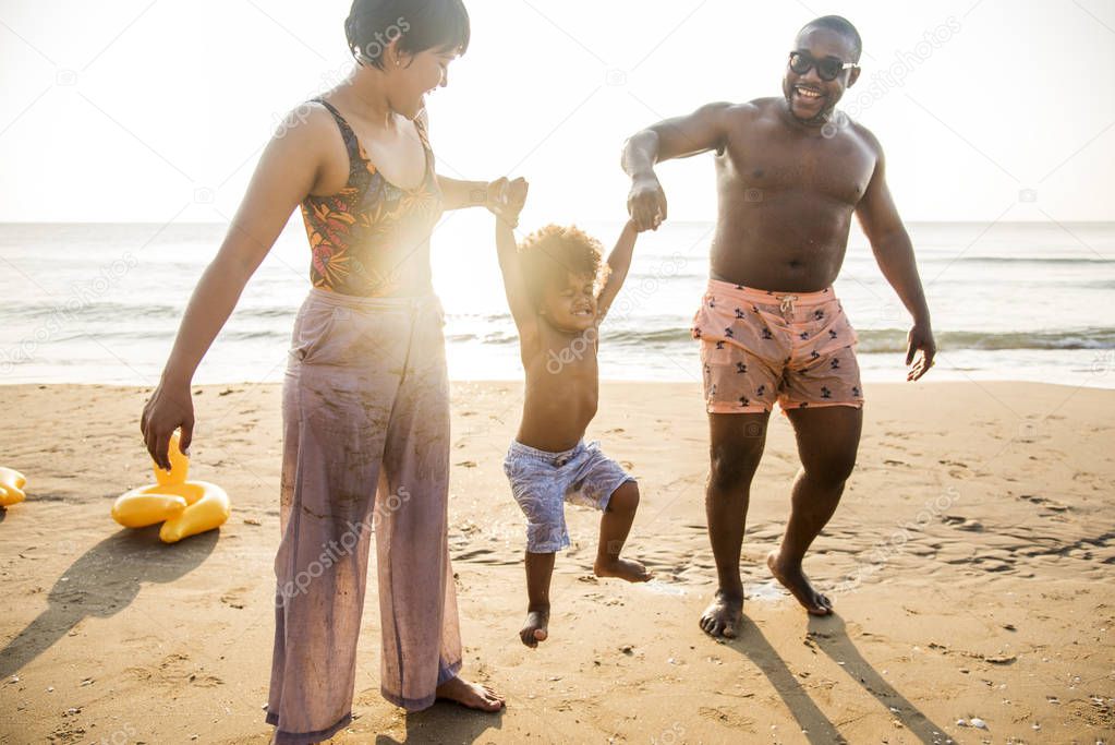 african american family enjoying beach in front of sunset sky