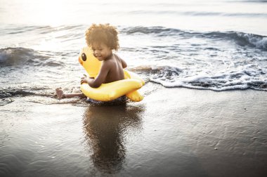 Kumsalda oturan ördek tüp ile şirin yürümeye başlayan çocuk
