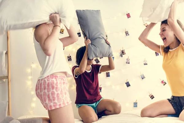 一组不同的妇女在床上玩枕头大战 — 图库照片