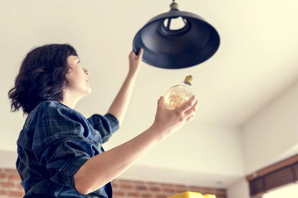 Woman changing light bulb