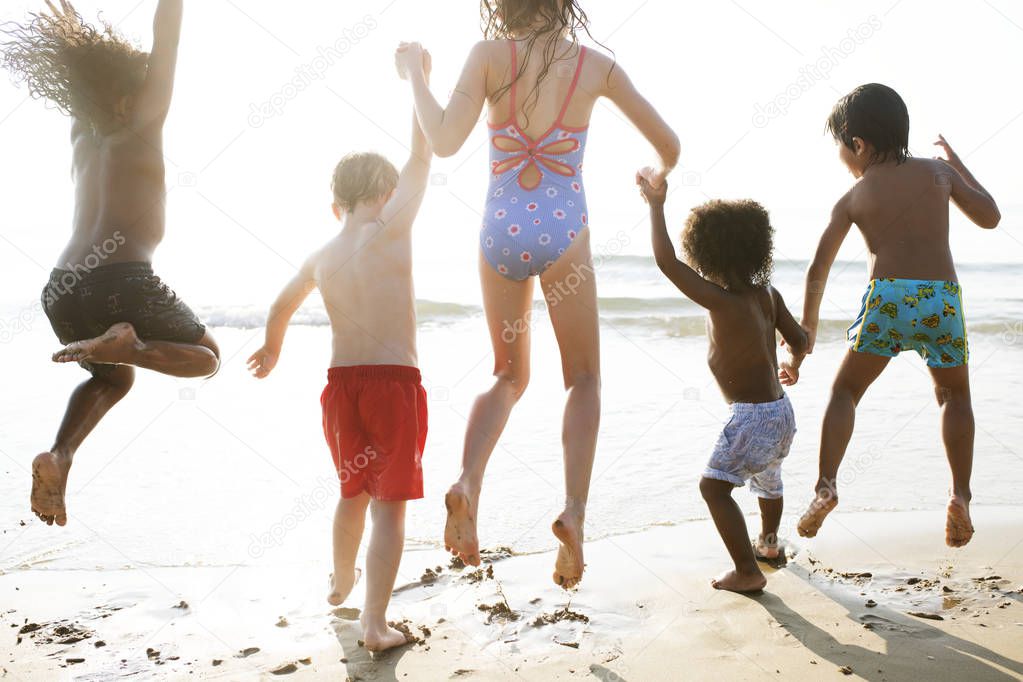 rear view of group of kids enjoying their time at beach
