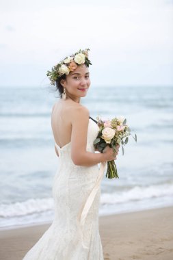Gelin Buketi kameraya kıyı şeridi üzerinde seyir ile çiçek çelenk içinde gülümseyen Genç gelin