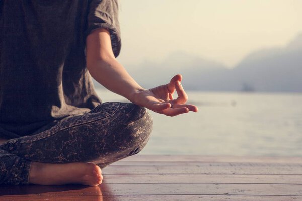 Woman practicing yoga by a lake