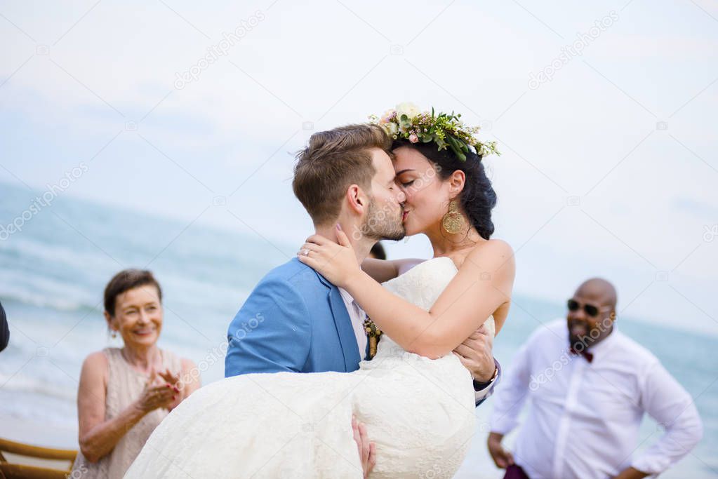 Cheerful newlyweds kissing at beach wedding ceremony