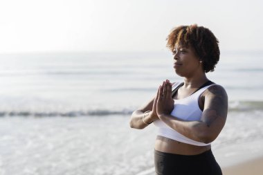 Afrikalı-Amerikalı kadın pratik yoga sahilde