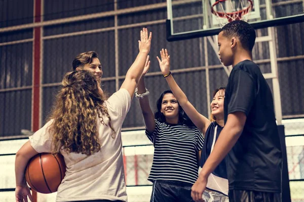 一群十几岁的朋友在一个篮球场给对方一个高五 — 图库照片