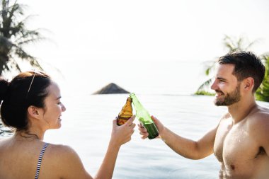 Havuzun kenarında bir bira olan genç çift