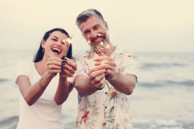 Couple celebrating with sparklers at the beach clipart