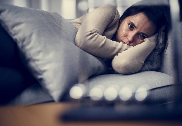 Depressed woman lying on sofa 