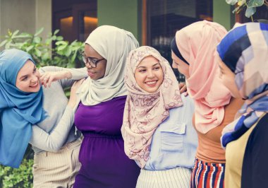 Grup İslami arkadaşları kollarını ve birlikte gülümseyen