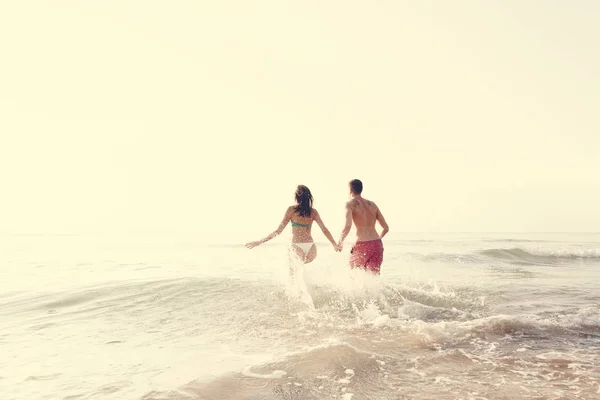 快乐的情侣跑入水中 — 图库照片