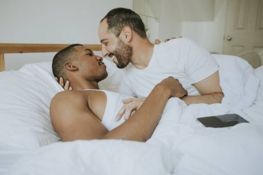 Gay couple cuddling in bed clipart