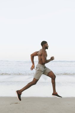Sabahın erken saatlerinde kumsalda koşan adam uygun