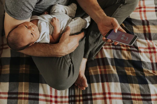 Pappa Håller Sin Baby Medan Använder Sin Telefon — Stockfoto