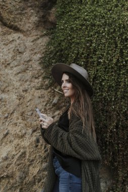 Büyük bir kaya tarafından akıllı telefon kullanan bir kadın 